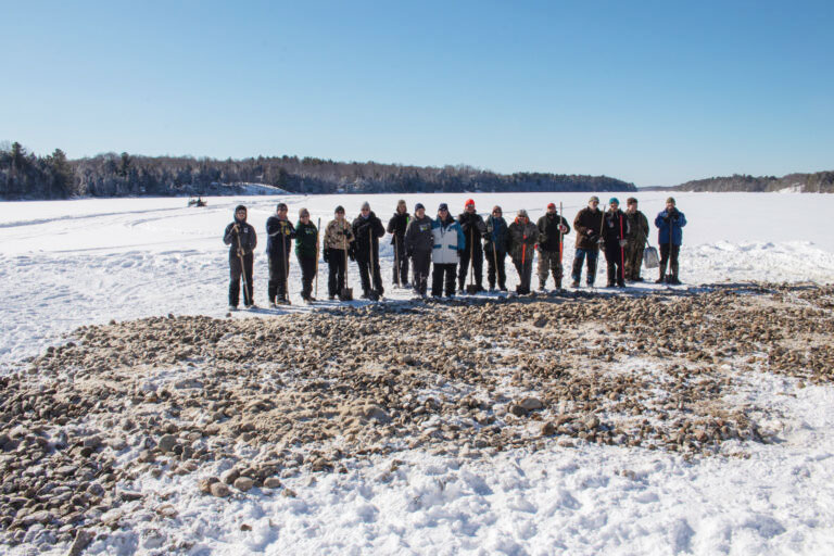 Volunteers work to spread gravel in an effort ot restore walleye spawning beds in Kennebec Lake