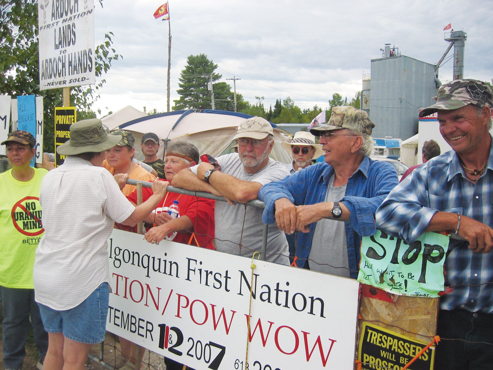 In September 2007, Shabot Obaadjiwaan and Ardoch Algonquins were joined by other anti-uranium activists at the Robertsville Mine site. The building in the back was a crushing mill.