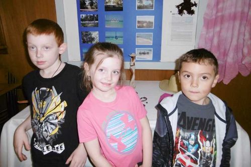 L to R. Hunter, Hailey and Brody are seen by a Cuban poster at World Day of Prayer in Parham United Church.