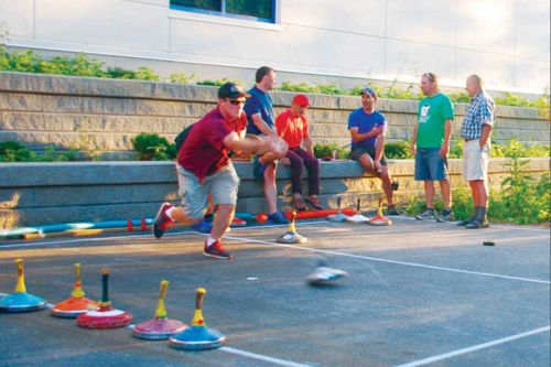 Karl Hammer making a throw, while in the background other players are discussing the finer points of the game.